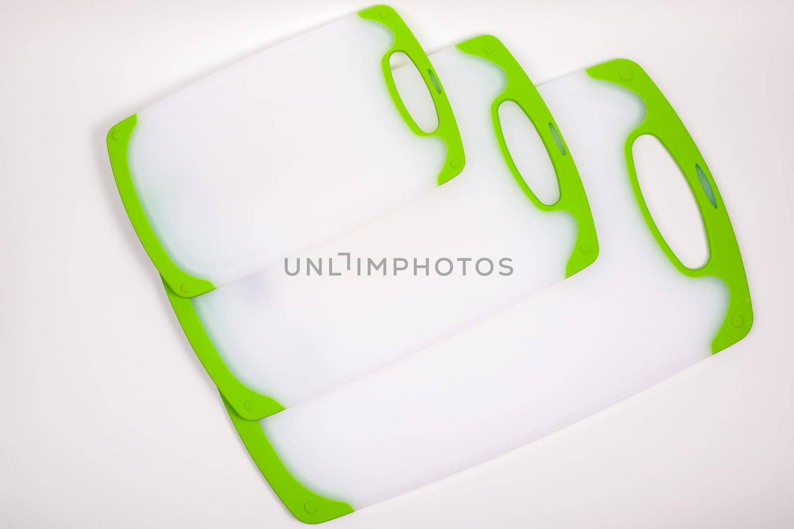 Set of white kitchen cutting boards with green handles for cooking. For cutting food, vegetables, meat, fish. Durable, professional, white plastic.