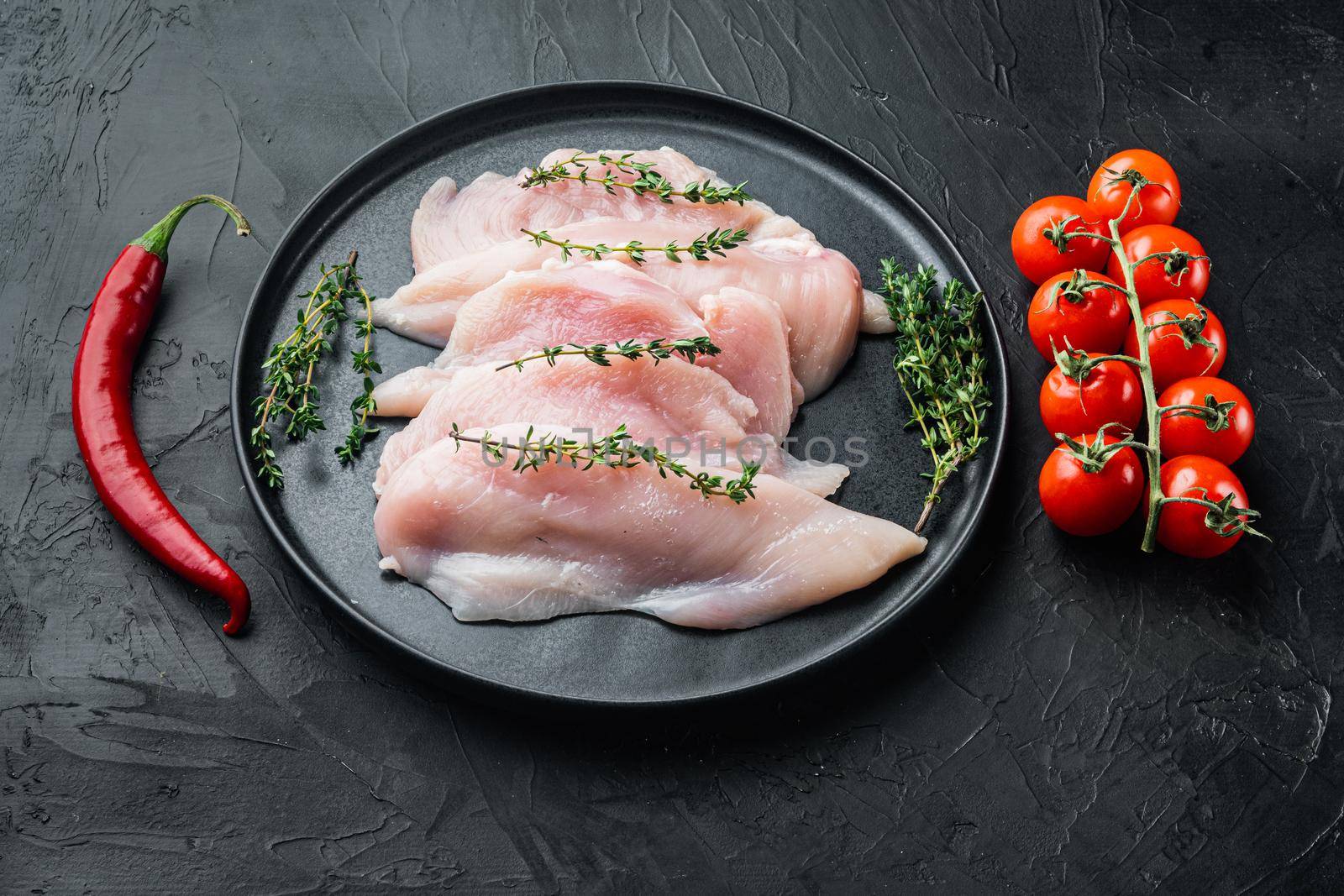 Raw chicken cutlet breast fillet, on black background
