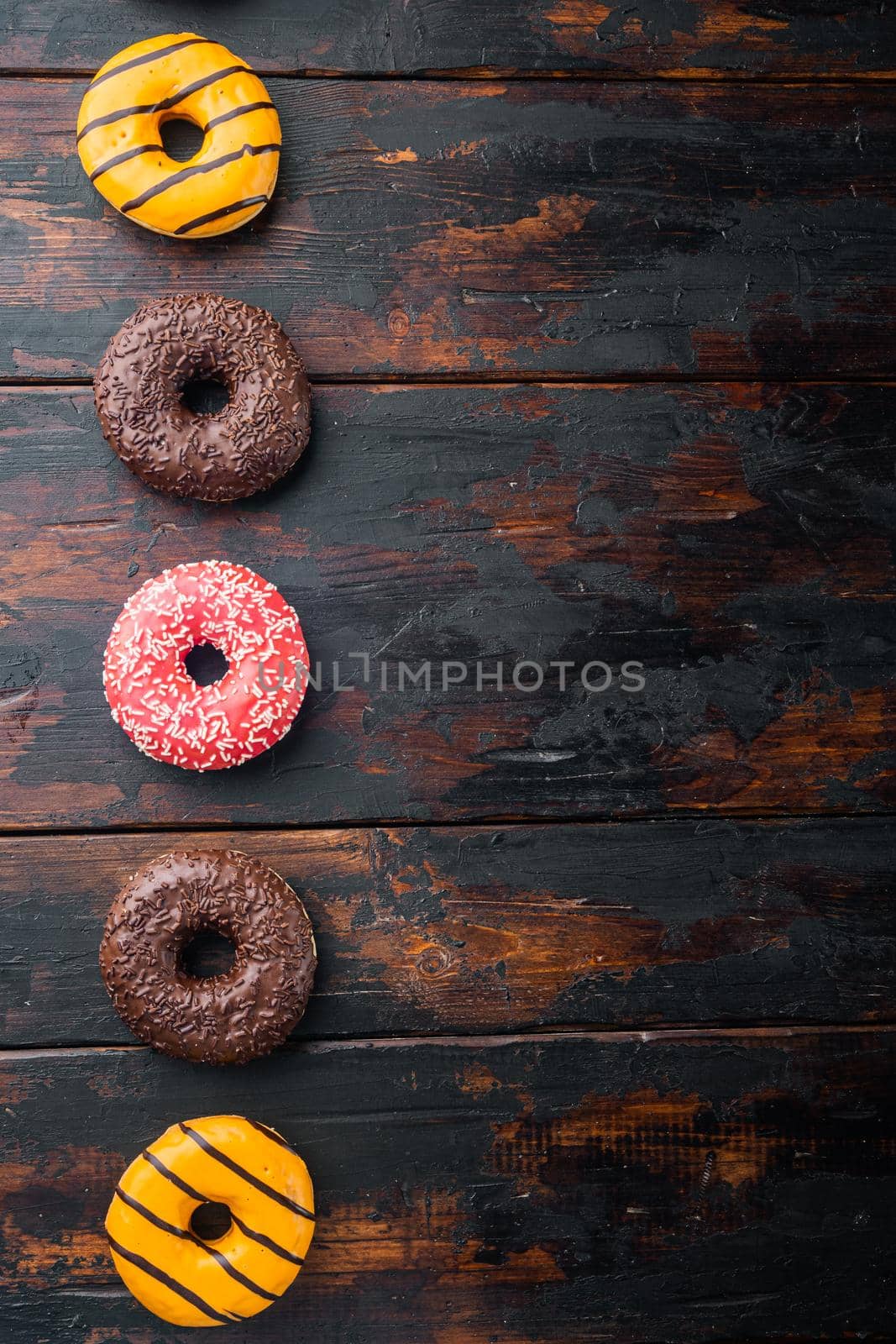 Delicious glazed donuts set, on old dark wooden table background, top view flat lay with copy space for text