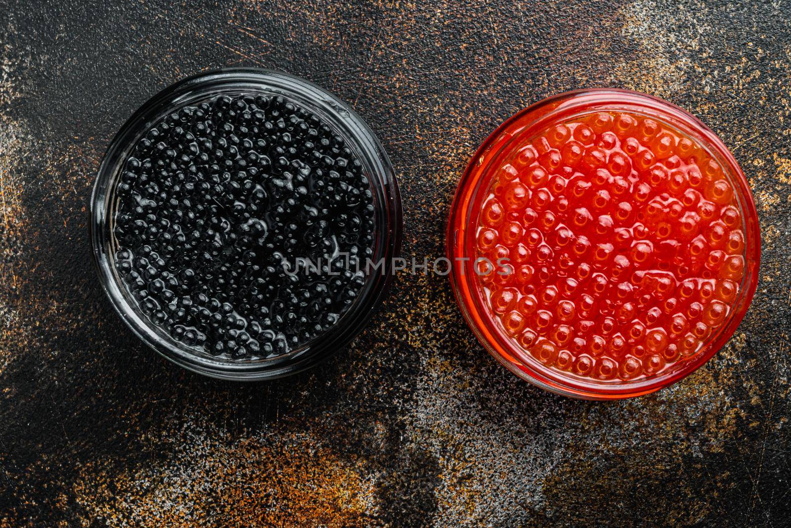 Glass jar with black and red caviar, on old dark rustic background, top view flat lay