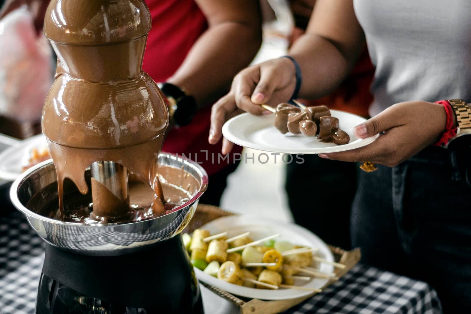 chocolate fountain catering machine with fruit skewers on rustic buffet table