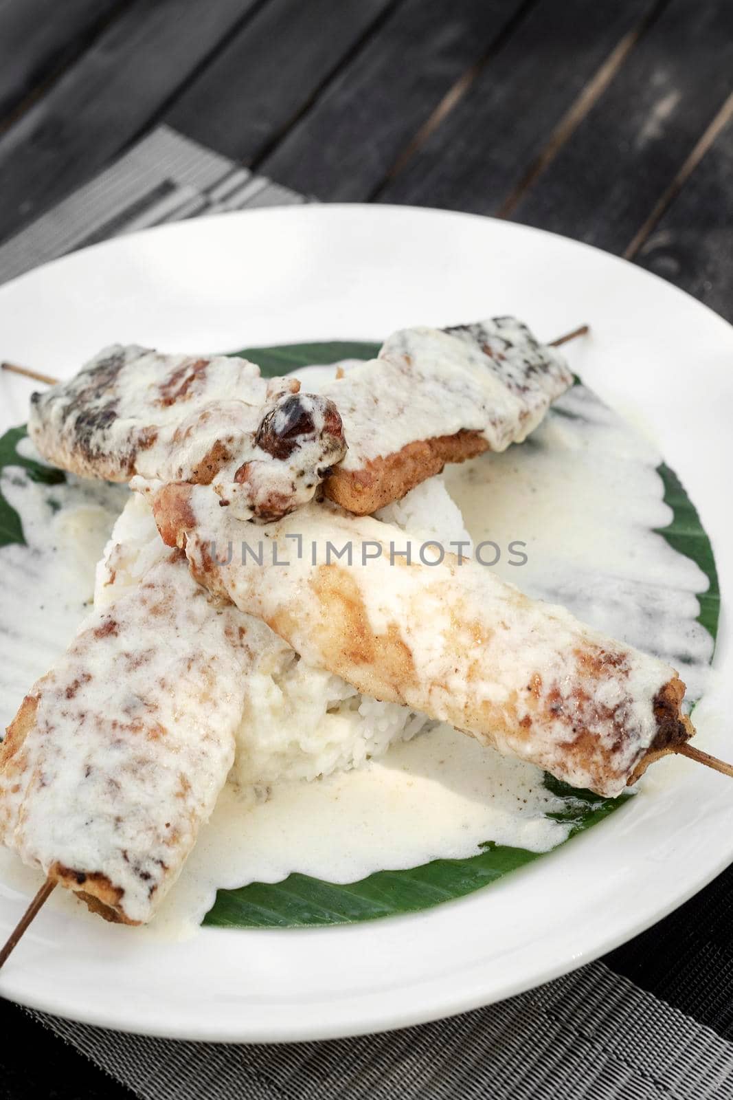 tropoical fish skewers with creamy coconut sauce and rice in vietnam restaurant