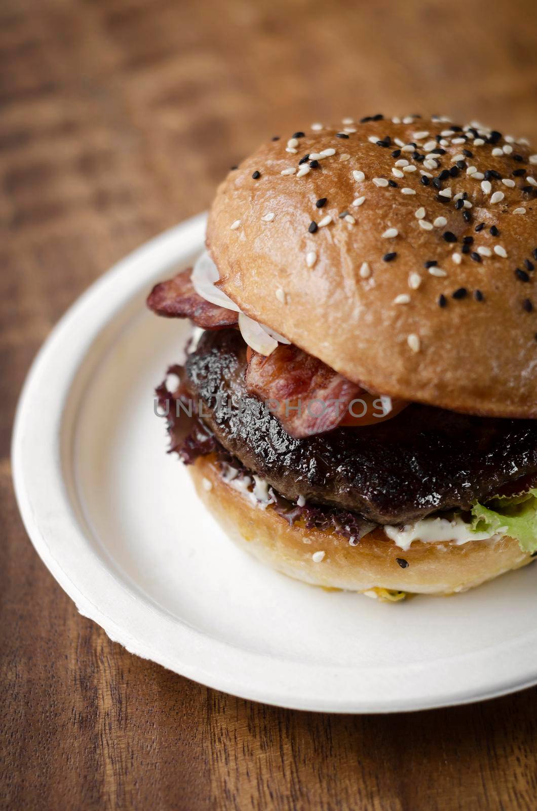 organic beef burger with bacon on wood table by jackmalipan