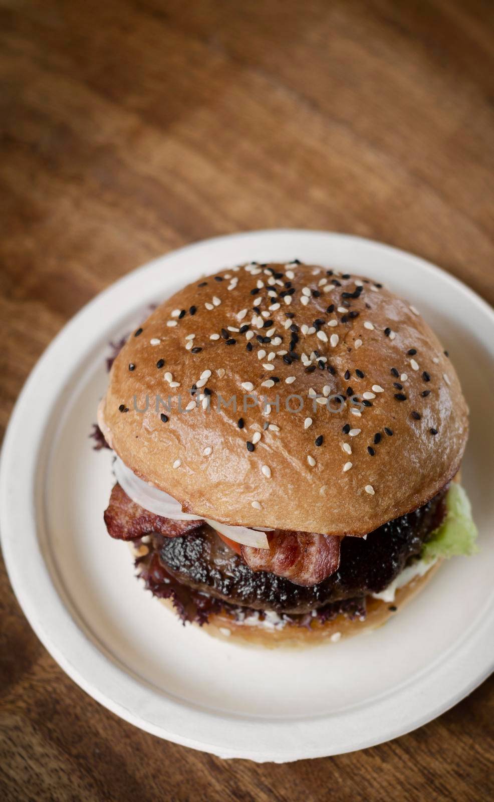 organic beef burger with bacon on wood table by jackmalipan