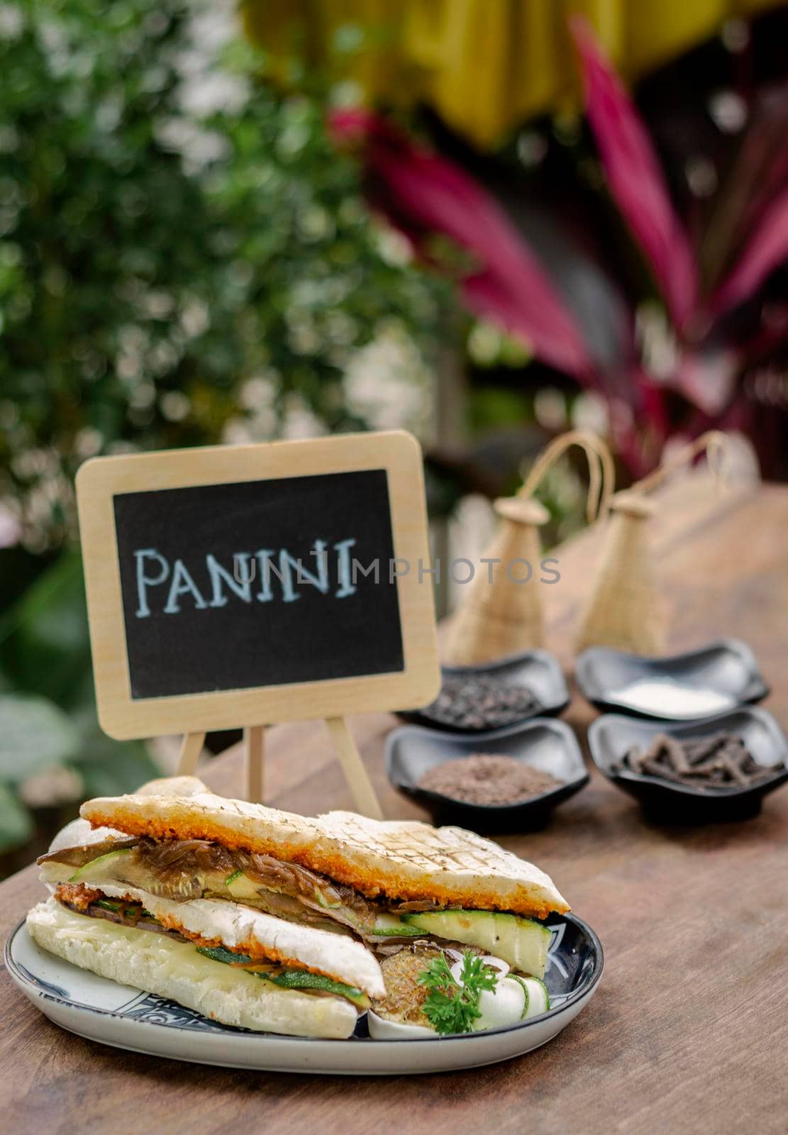 vegan roasted vegetable toasted panini sandwich on wood table outdoors by jackmalipan