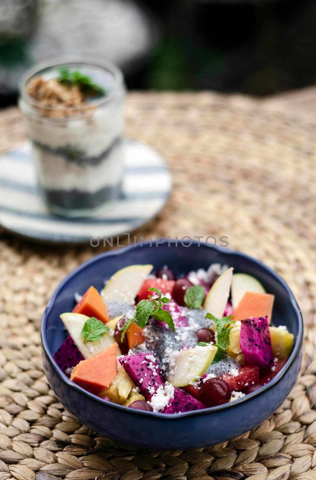 exotic mixed tropical asian fruit salad with basil seeds and coconut in bowl outdoors