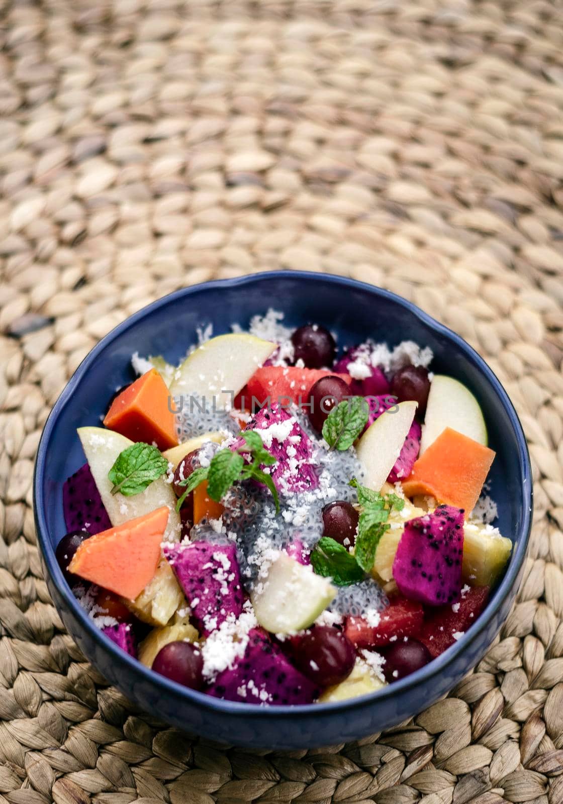 exotic mixed tropical asian fruit salad with basil seeds and coconut in bowl outdoors