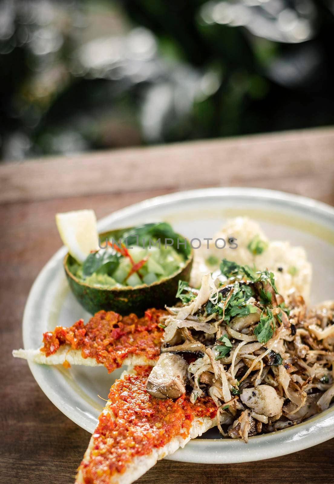 modern mexican brunch of  fried mushrooms with guacamole and spicy red pepper paste toast and scrambled eggs