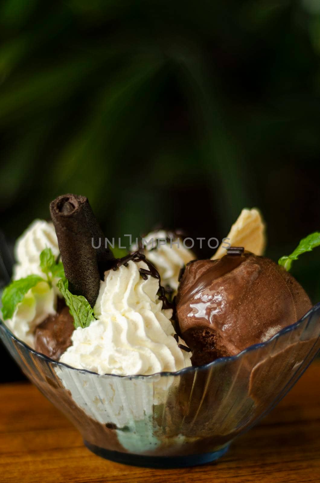 chocolate and mint ice cream sundae dessert on wooden table by jackmalipan