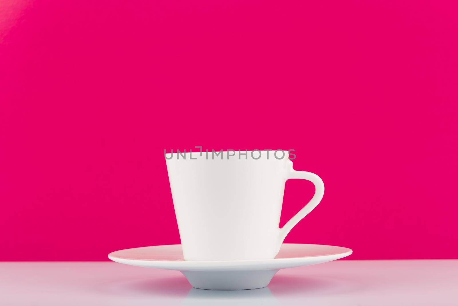 White ceramic coffee cup with saucer against pink background with copy space by Senorina_Irina