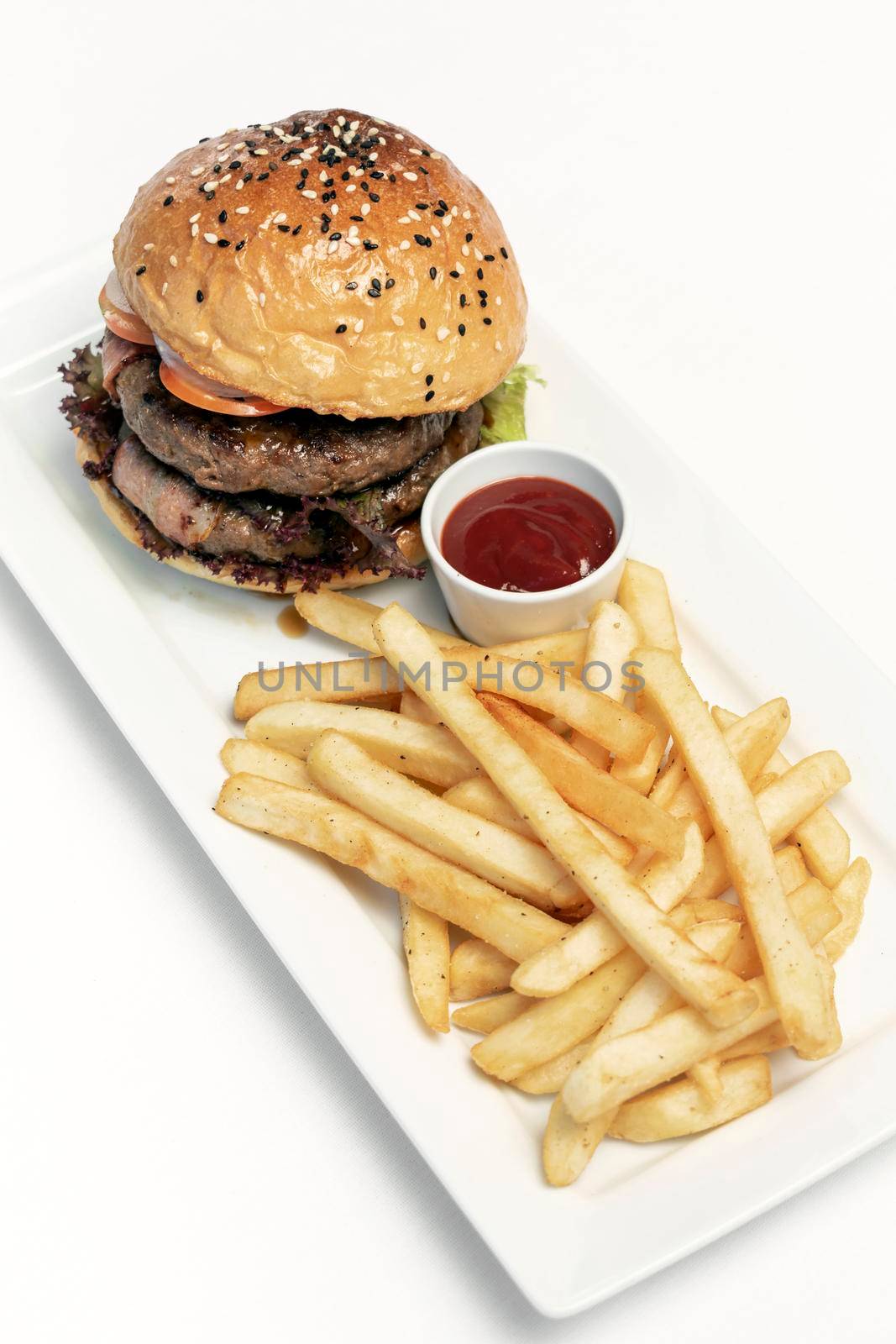 beef burger with french fries platter on white table by jackmalipan