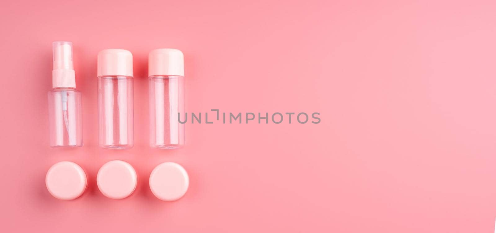 Empty plastic bottles and tubes for cosmetic on pastel pink background with copy space, top view flat lay, banner