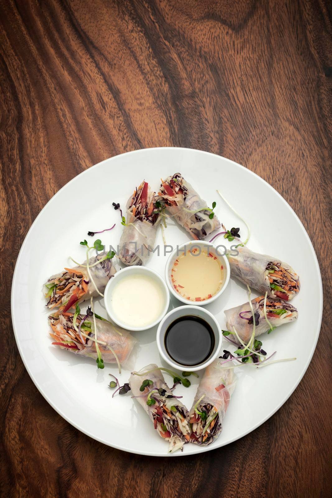 asian fresh vegetable vegan spring rolls with sauces on wood restaurant table background in vietnam