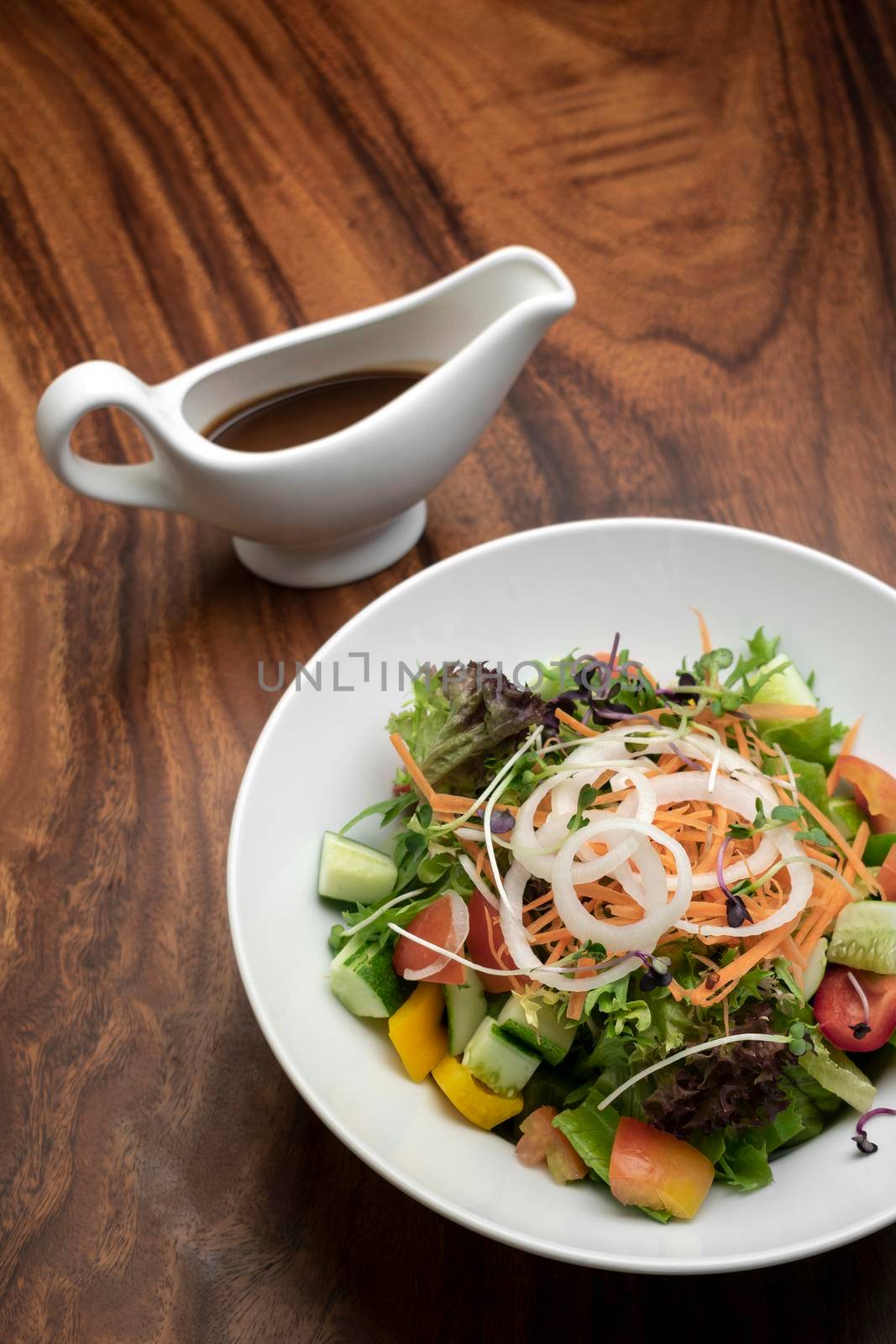 fresh organic mixed vegetable vegan Garden Salad with Vinaigrette sauce on wooden table