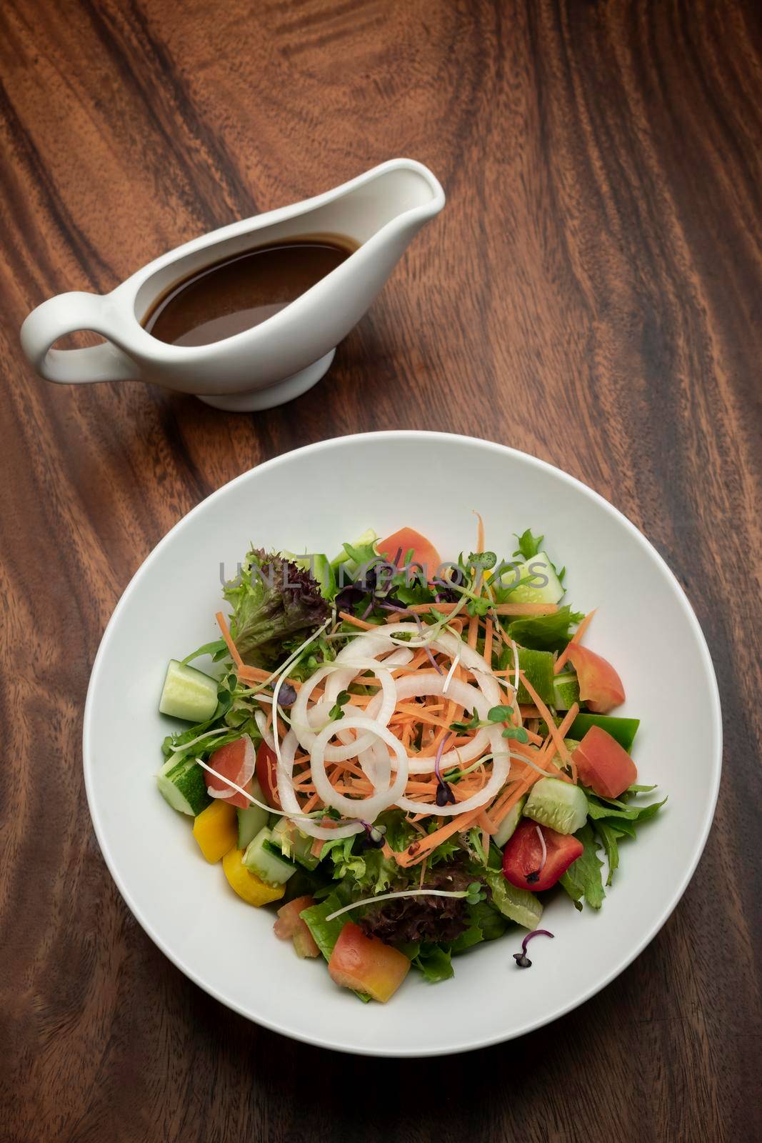 fresh organic mixed vegetable vegan Garden Salad with Vinaigrette sauce on wooden table
