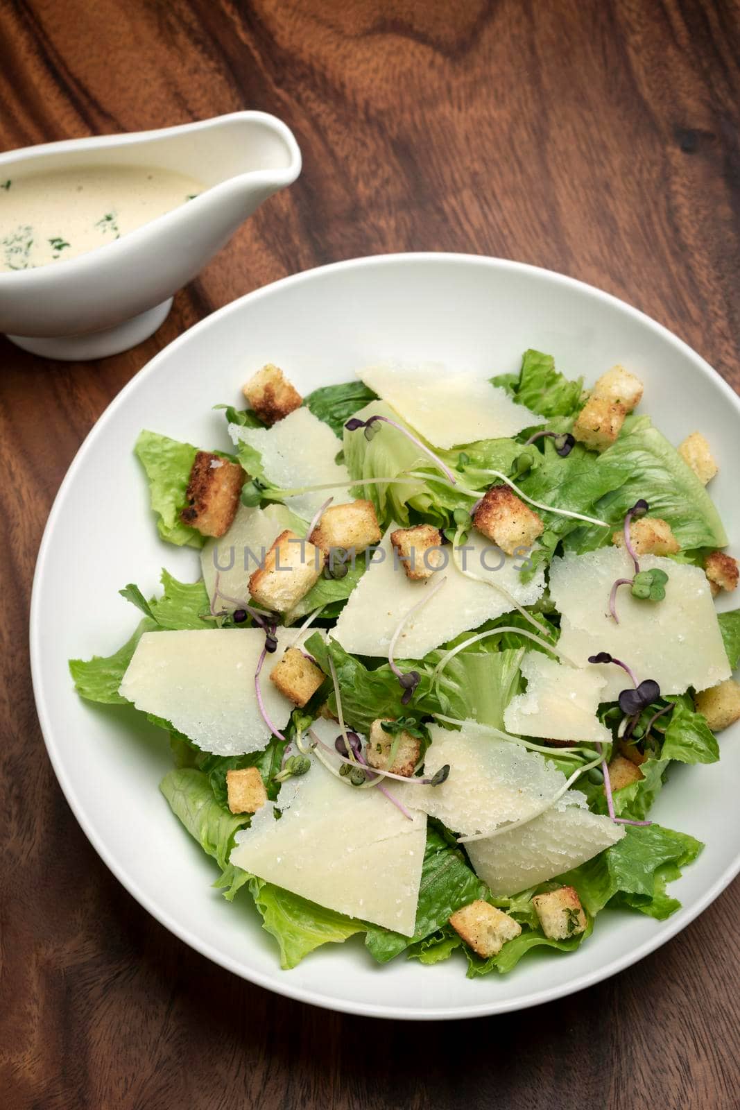 caesar salad with parmesan cheese and croutons on wood table