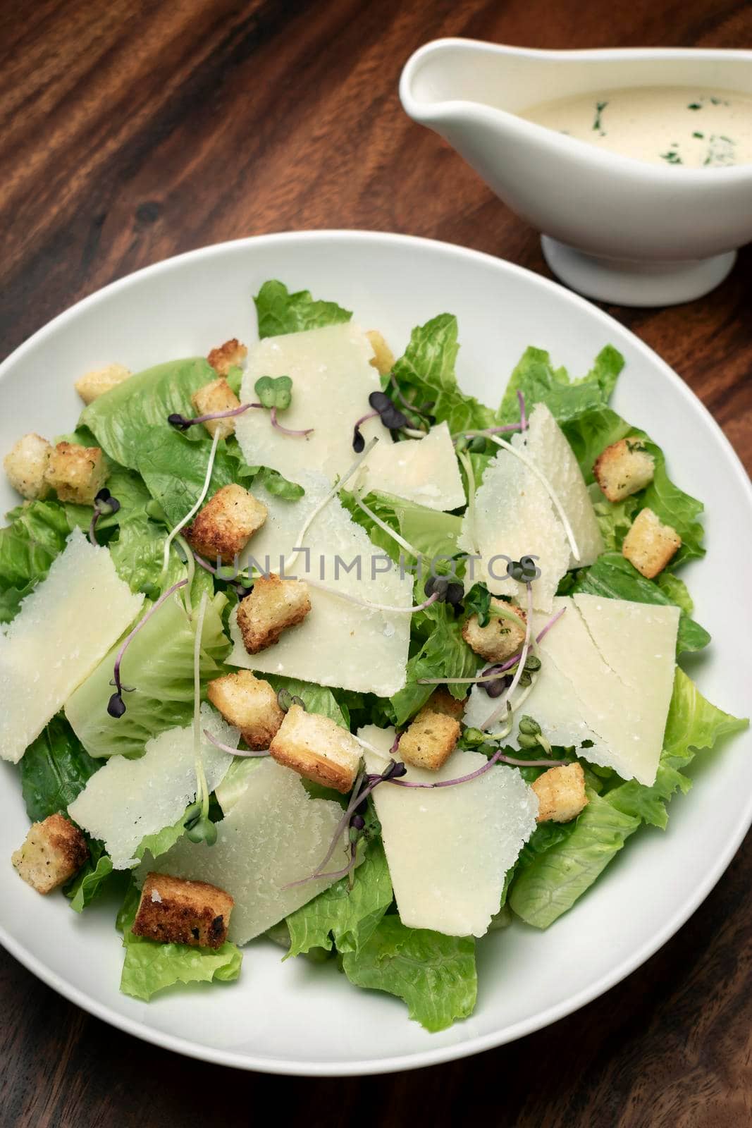 caesar salad with parmesan cheese and croutons on table by jackmalipan