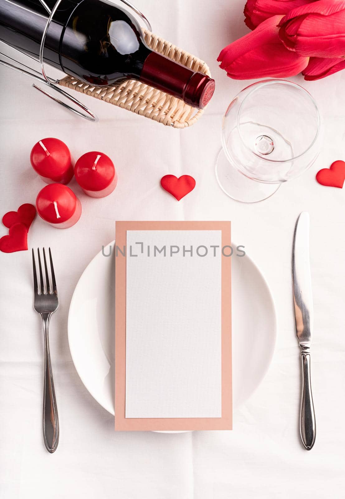 Valentines Day and Womens Day concept. Valentines day table setting with menu, plate, bottle of wine top view, mock up design