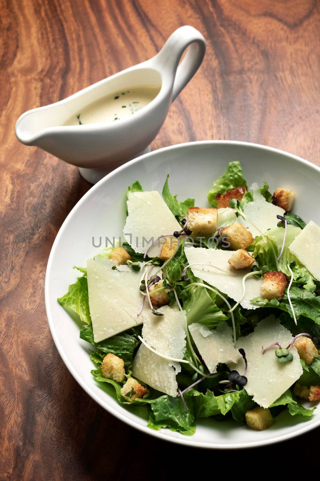 caesar salad with parmesan cheese and croutons on table by jackmalipan