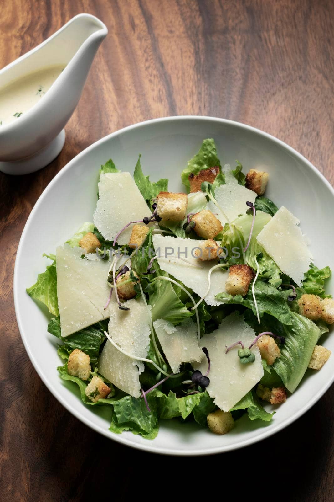 caesar salad with parmesan cheese and croutons on table by jackmalipan