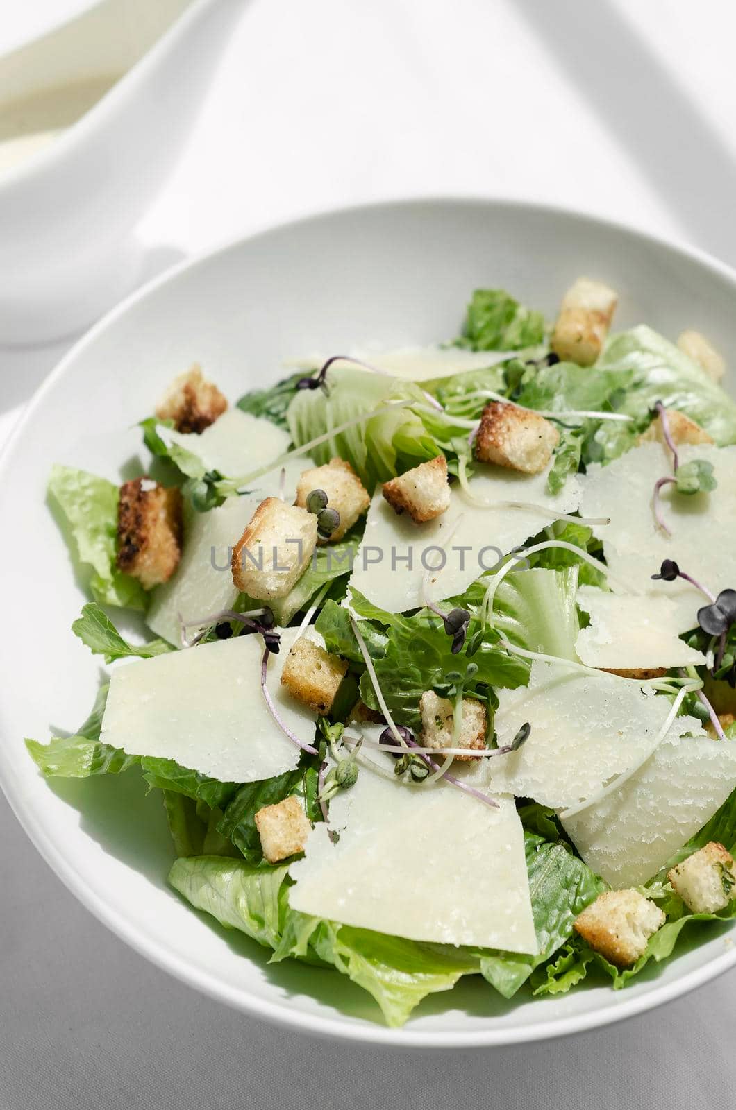 caesar salad with parmesan cheese and croutons on table
 by jackmalipan