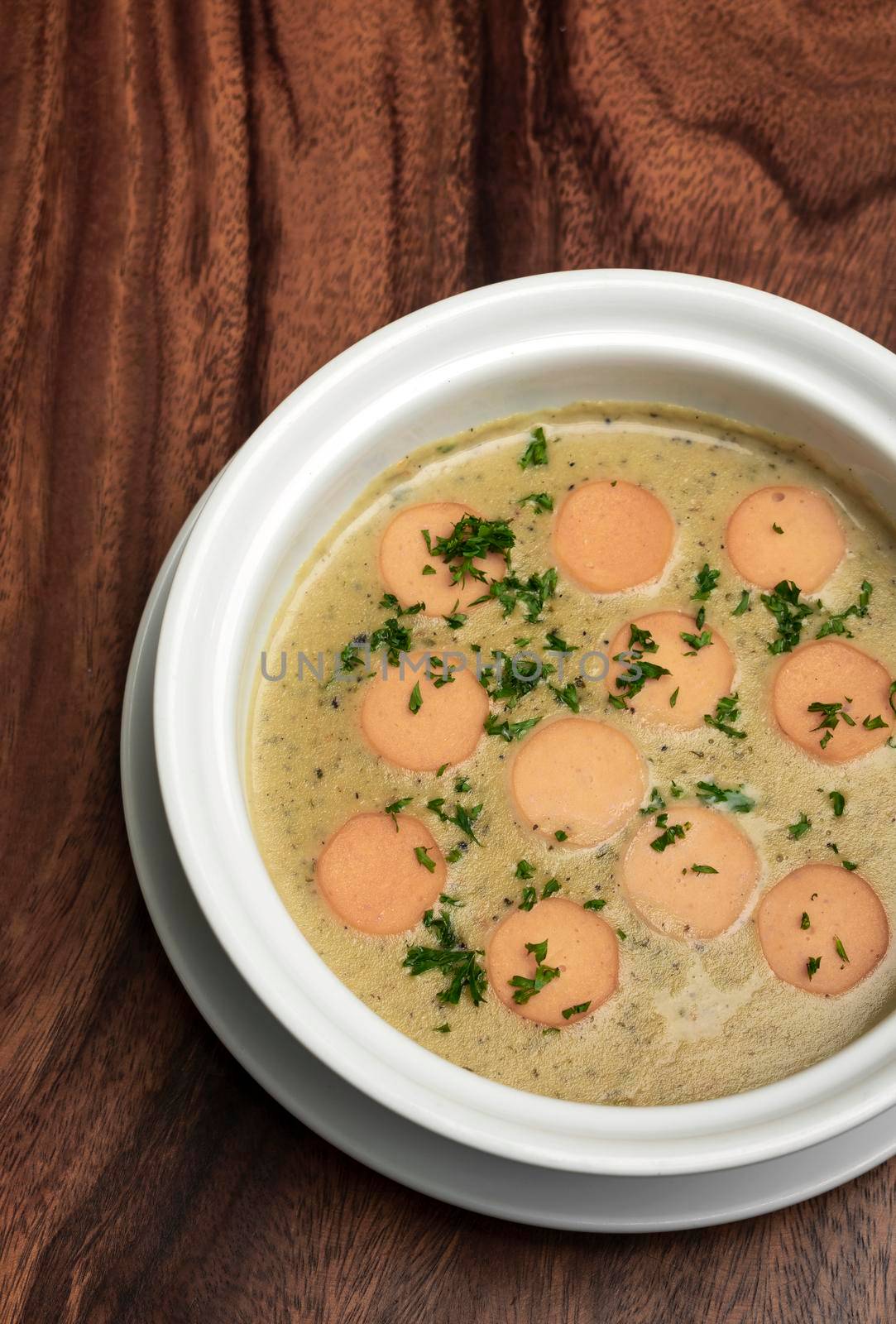 German traditional KARTOFFELSUPPE potato and sausage soup on wood table background