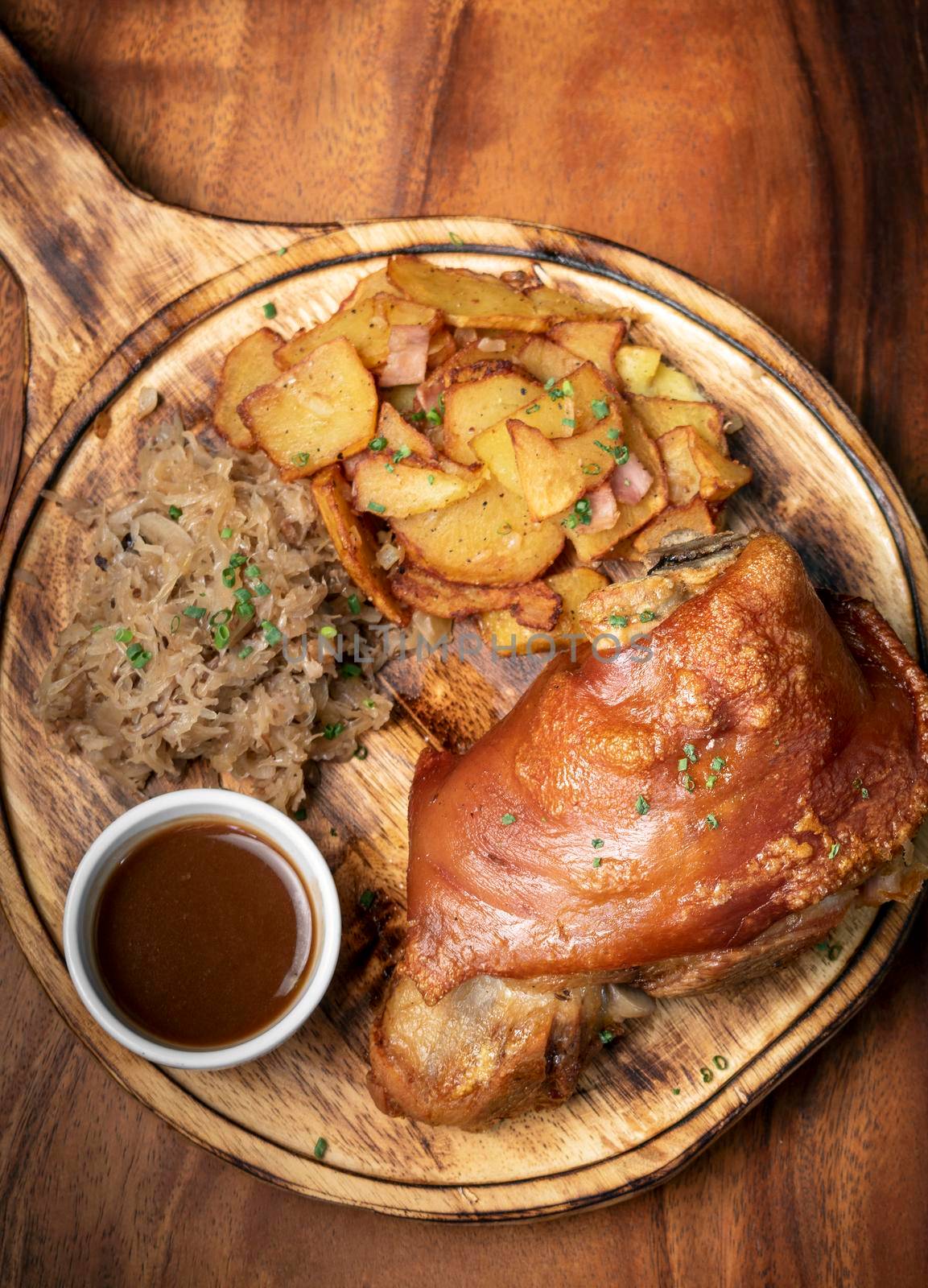 SCHWEINSHAXE traditional german pork knuckle with sauerkraut and potatoes bavarian meal on rustic wood background