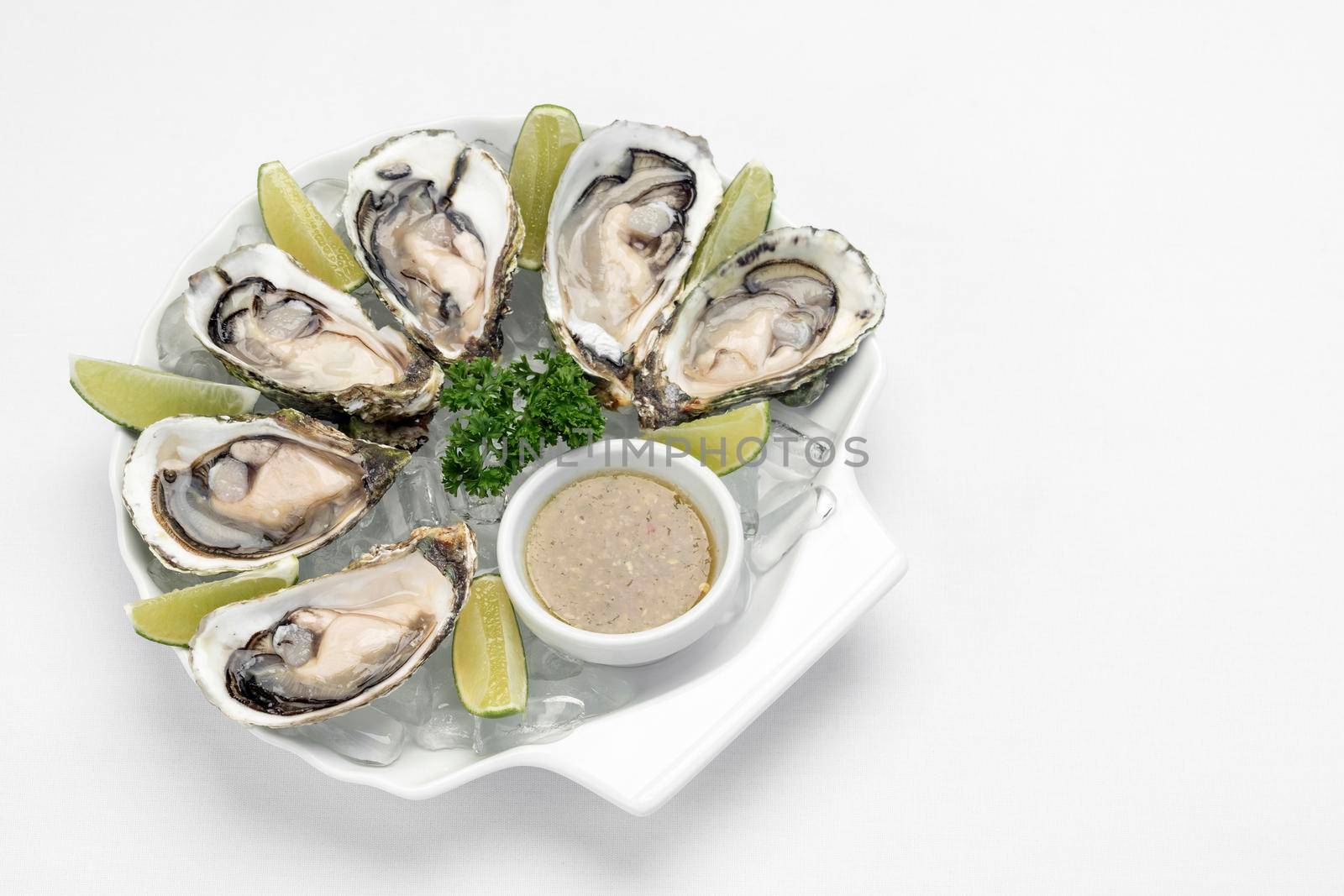 Six fresh oysters with lime wedges and citrus vinaigrette sauce