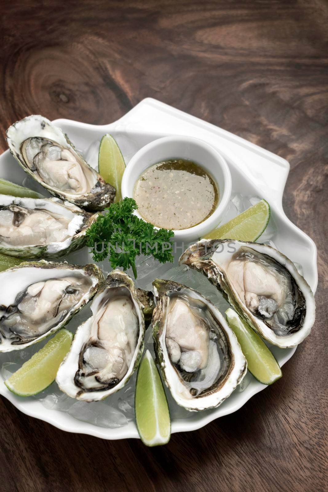 Six fresh oysters with lime wedges and citrus vinaigrette sauce