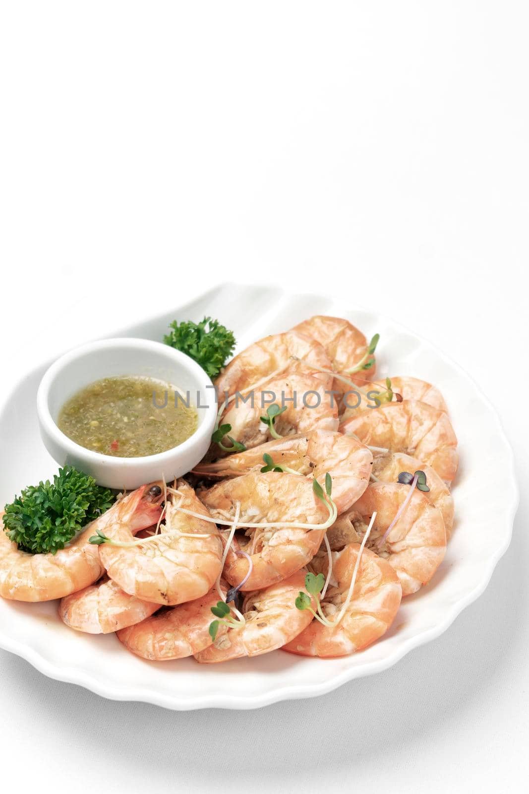 fresh boiled prawns with zesty citrus dipping sauce on white background