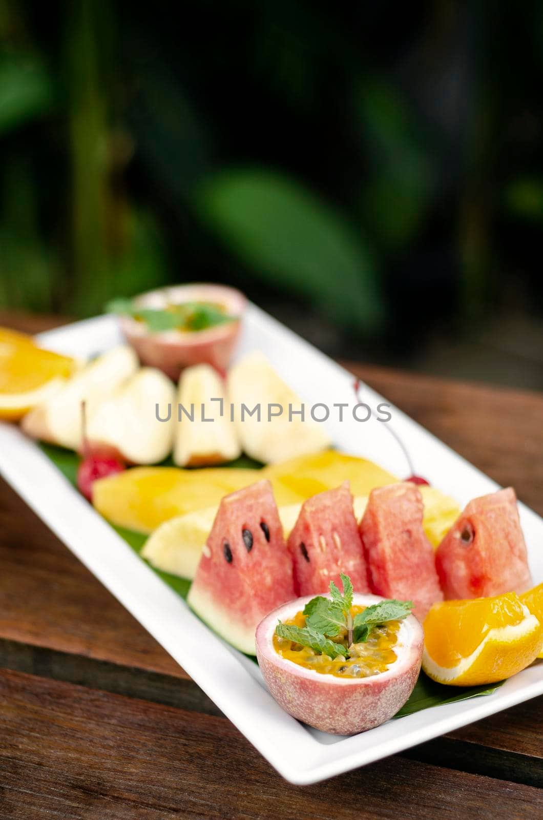 mixed fresh cut organic fruit salad platter outdoors on wood table