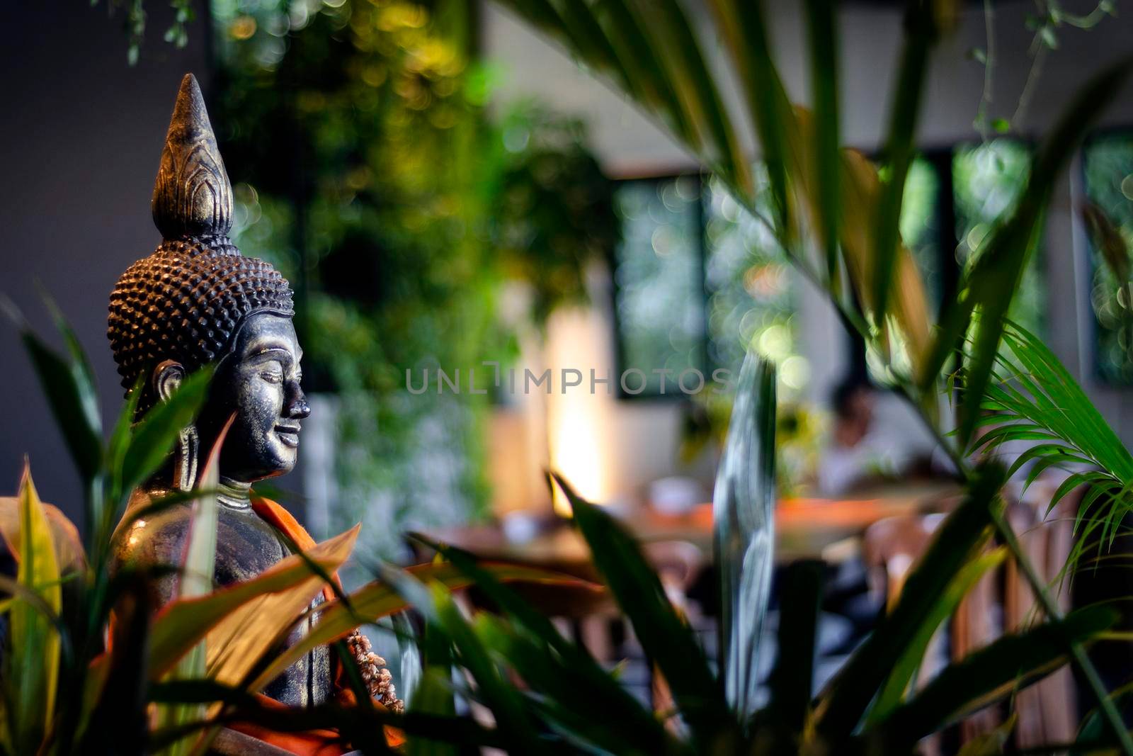 buddha statue in interior garden at tropical bar in bangkok thailand