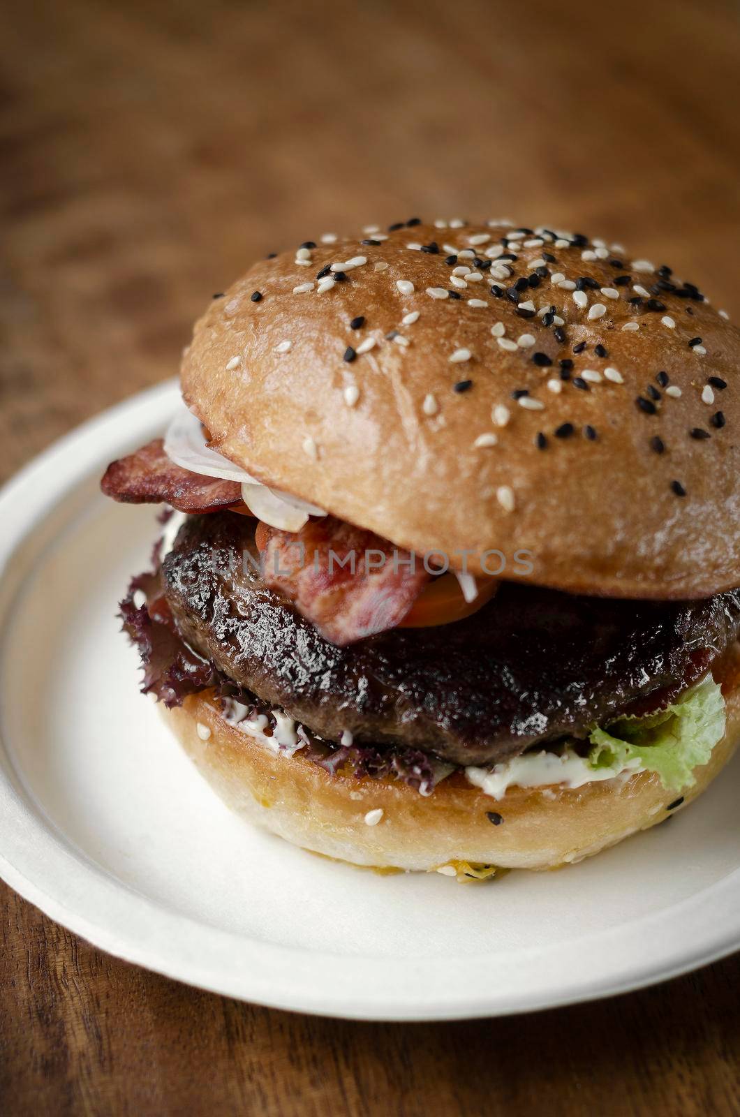 organic beef burger with bacon on wood table by jackmalipan