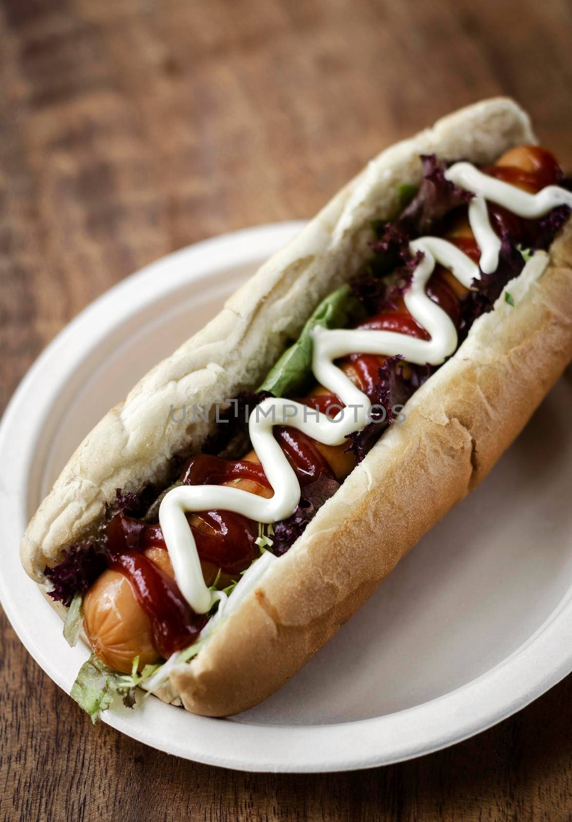 classic hot dog with frankfurter sausage and sauces on wood table