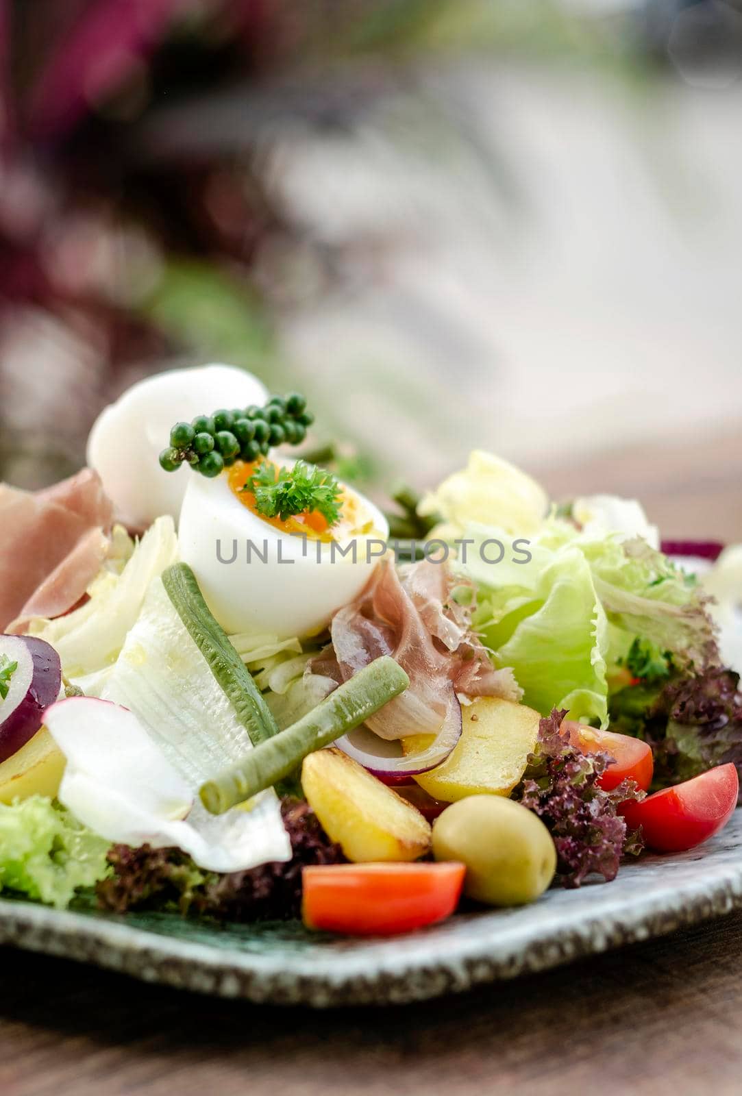 nicoise style healthy organic salad with egg and ham outdoors by jackmalipan