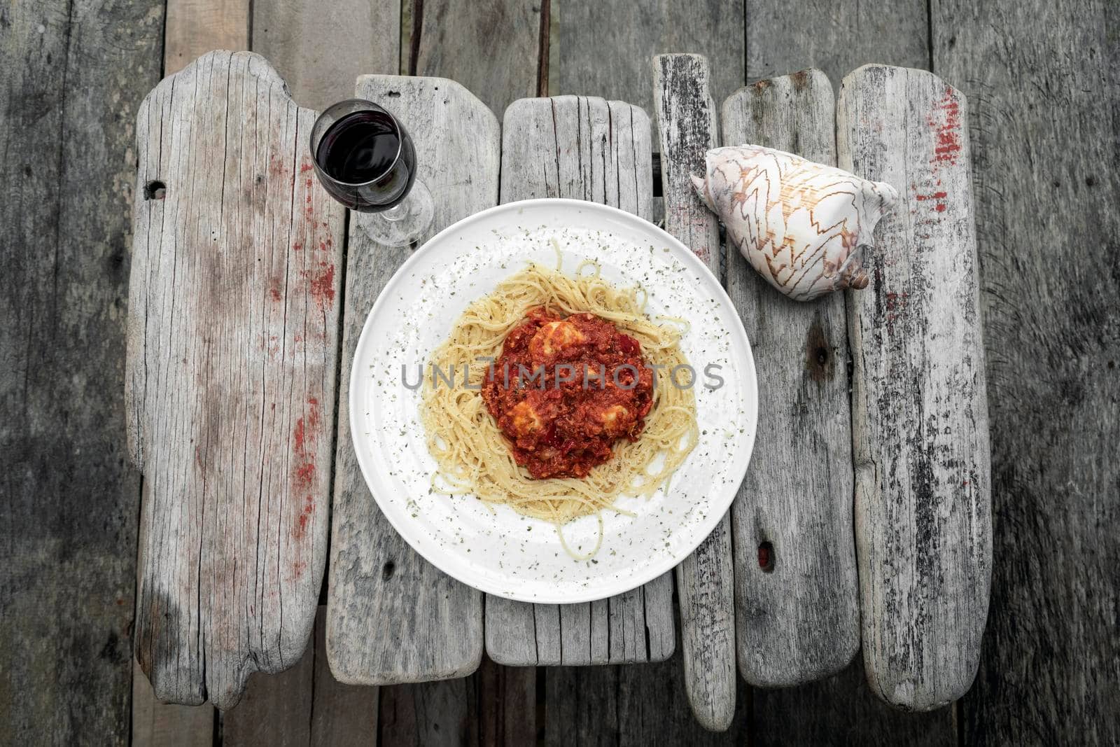 mozzarella bocconcini balls in tomato vegetable ragu sauce with spaghetti  and glass of red wine on rustic old wood table