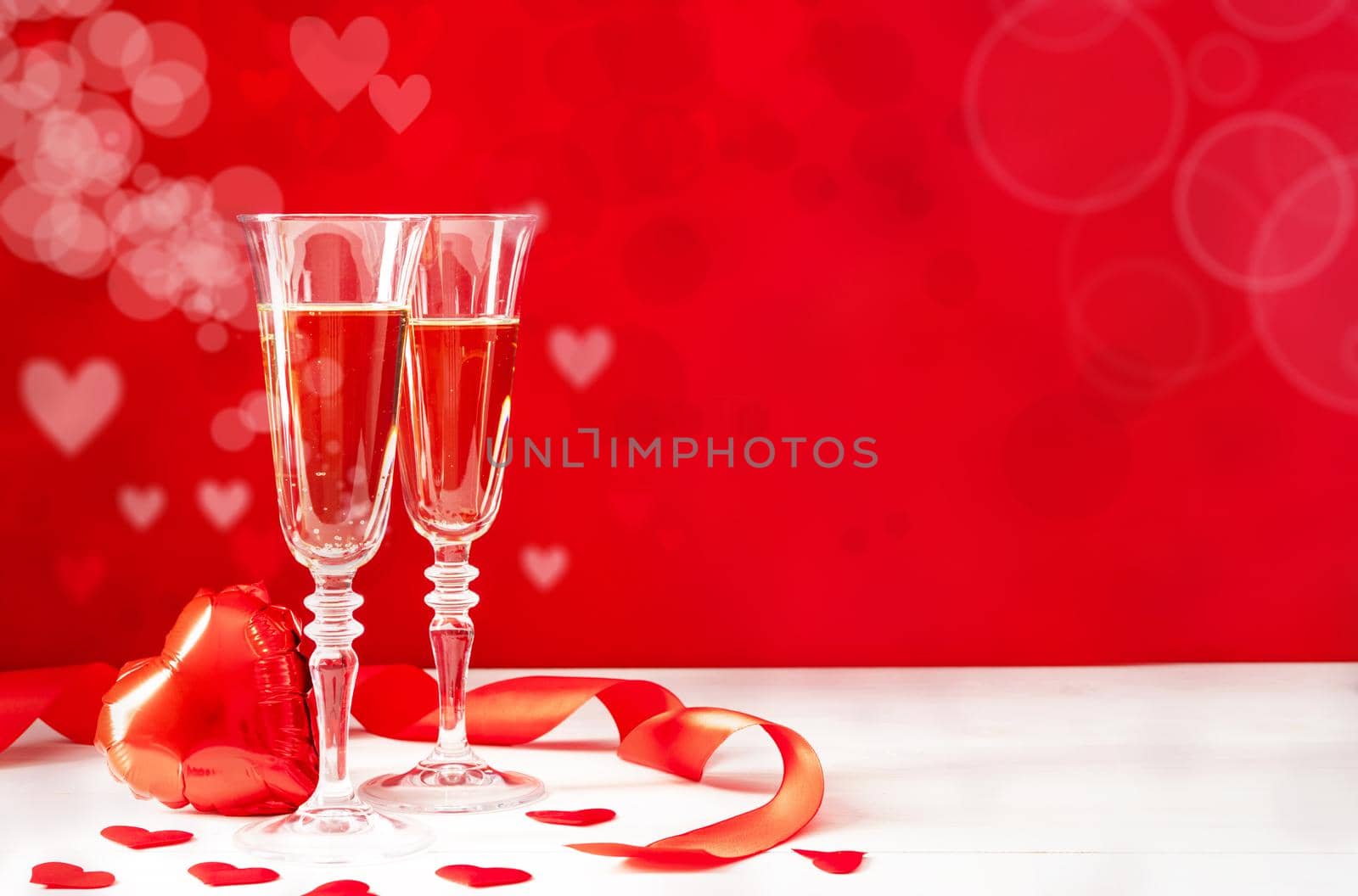 Valentines Day. Two champagne glasses, gift boxes and candles on beautiful bokeh background with copy space