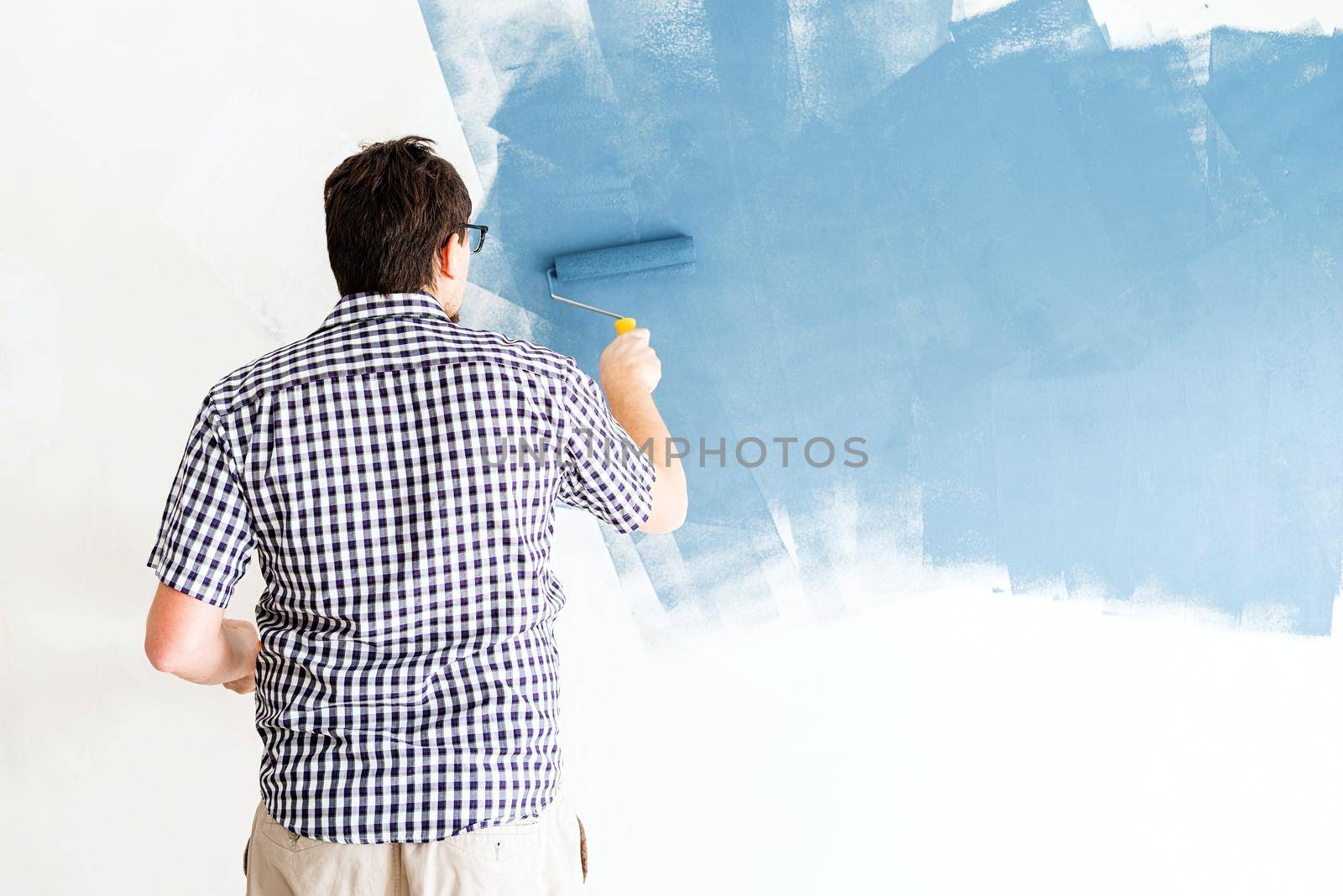 Home repair and improvement. Man coloring wall blue with a roller