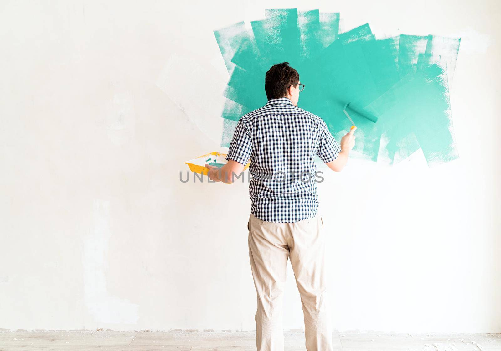 Man coloring wall green with a roller by Desperada