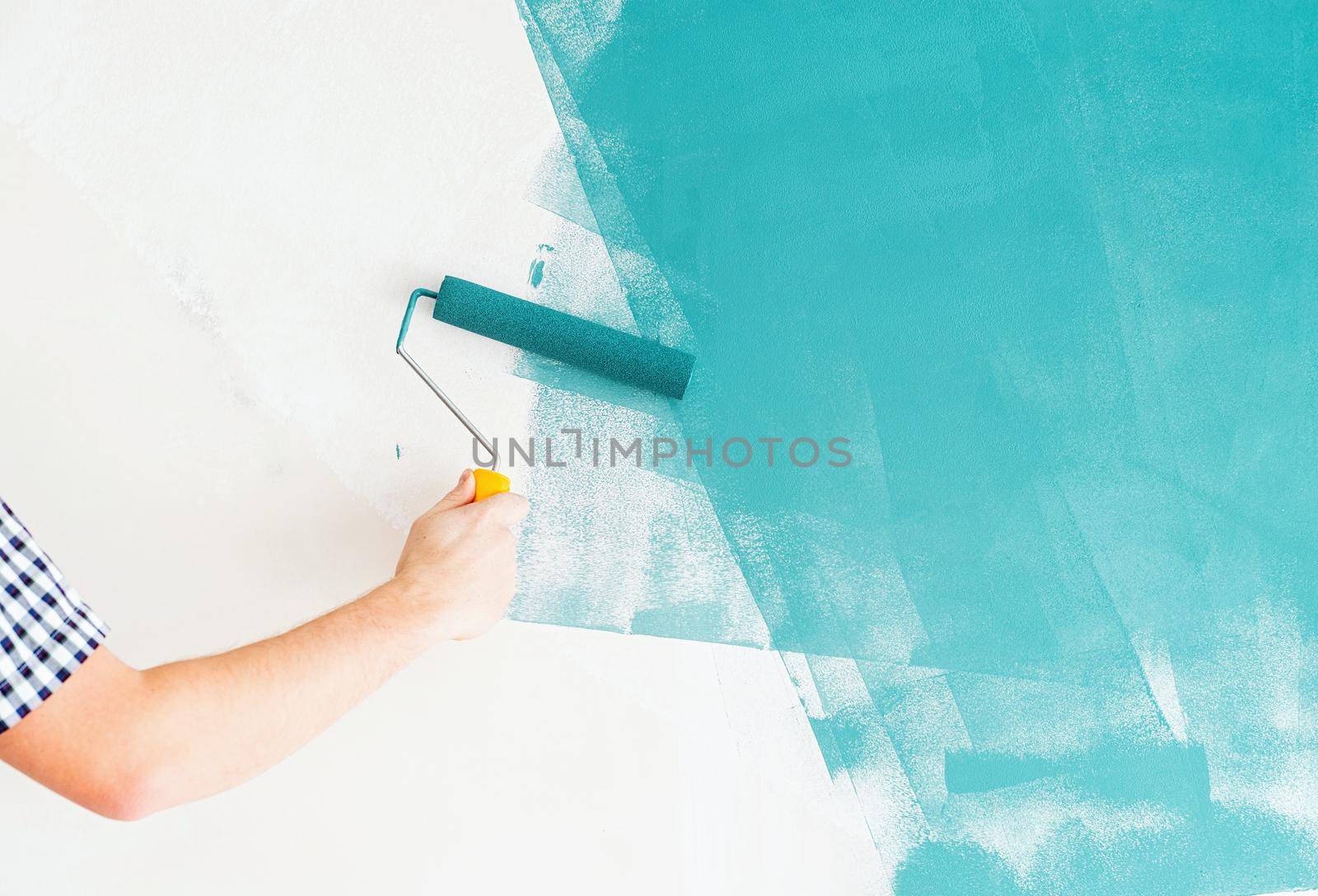 Man coloring wall blue with a roller by Desperada