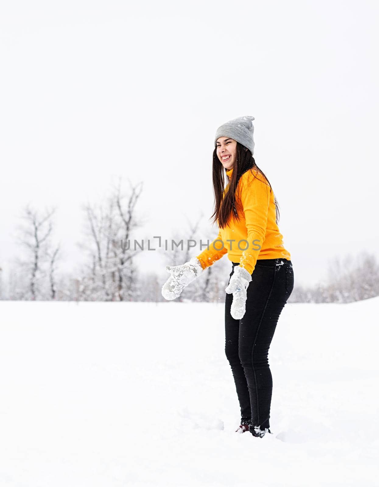 Winter season. Young brunette woman playing with snow in park