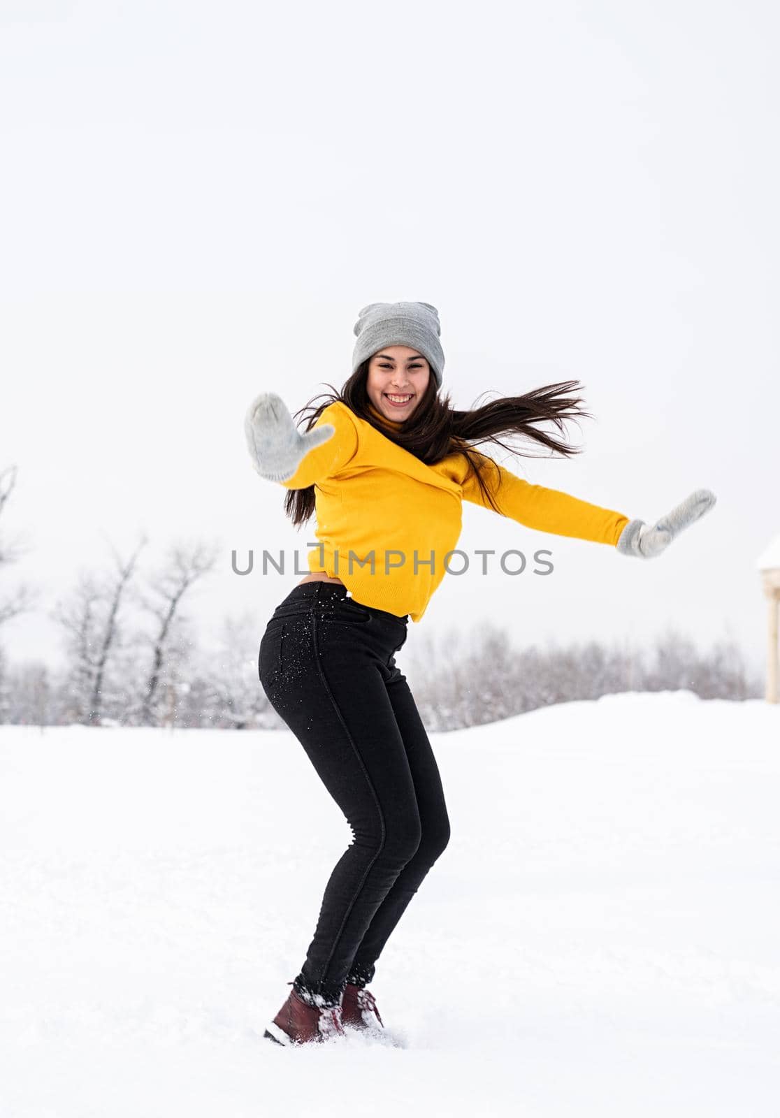 Young brunette woman playing with snow in park by Desperada