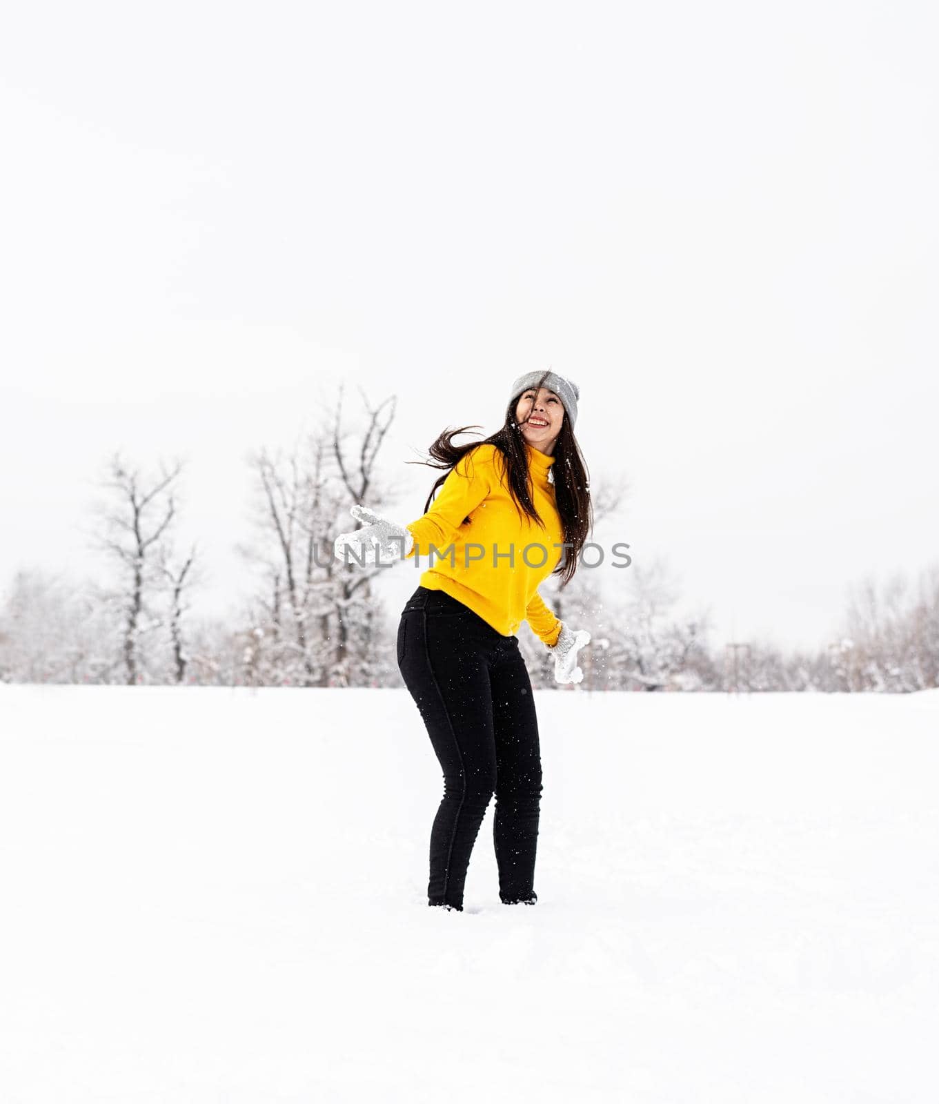 Young brunette woman playing with snow in park by Desperada