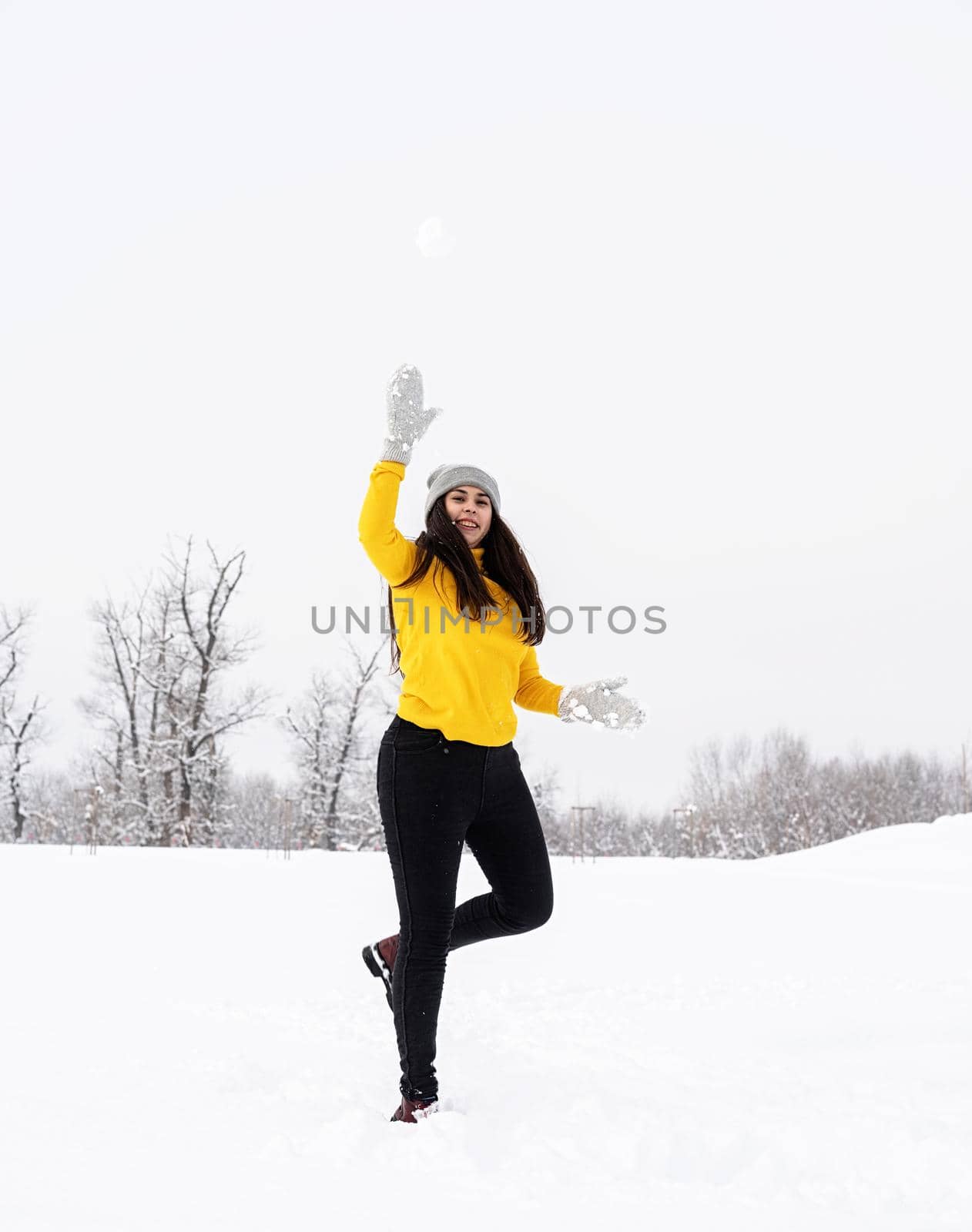 Young brunette woman playing with snow in park by Desperada