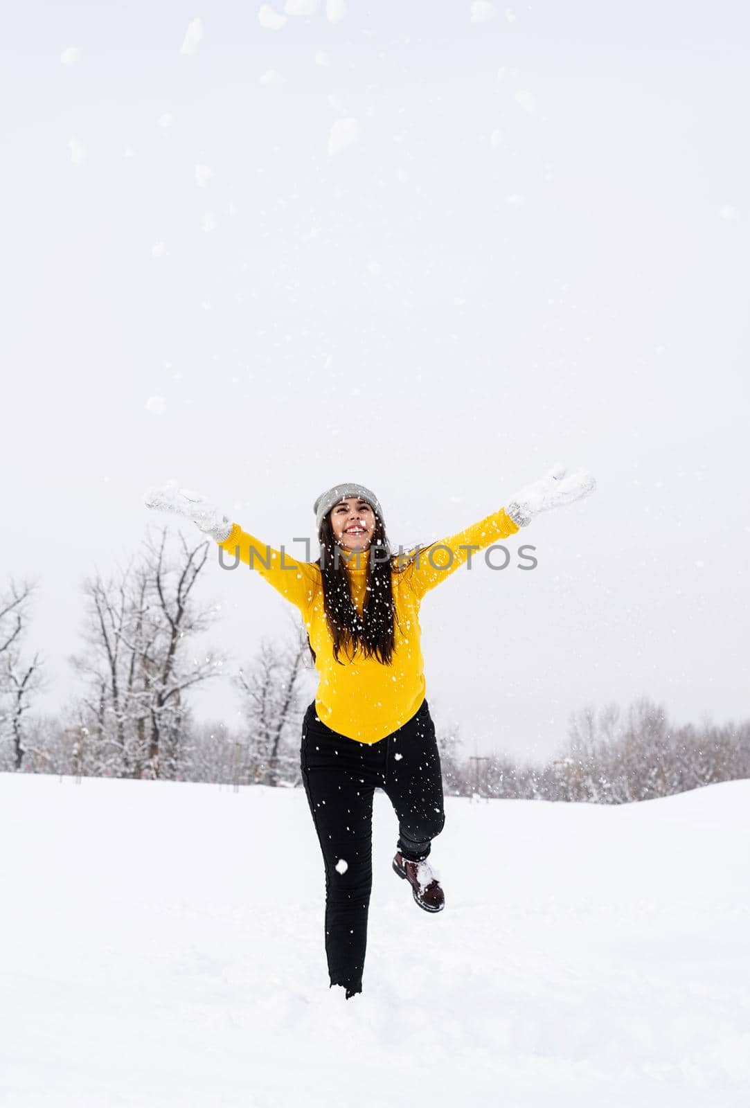 Young brunette woman playing with snow in park by Desperada