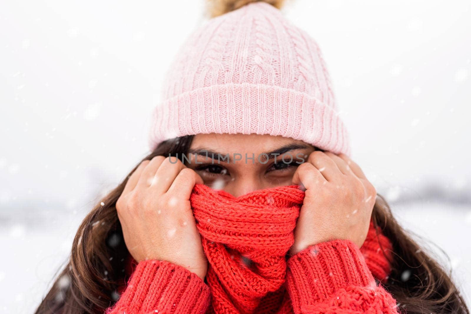 Winter season. Portrait of a beautiful smiling woman in red sweater and hat in snowy park