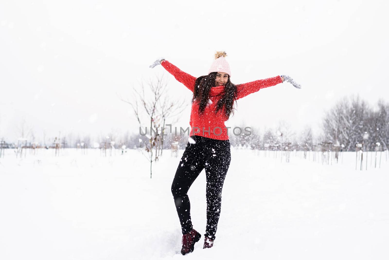 Winter season. Young brunette woman in red sweater playing with snow in park