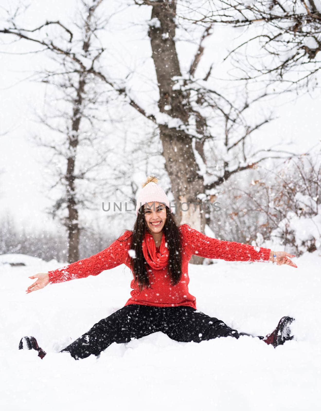 Winter season. Young brunette woman in red sweater playing with snow in park