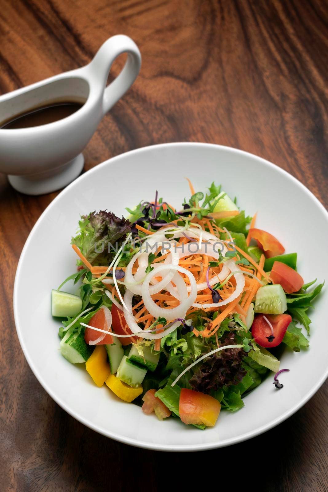 fresh organic mixed vegetable vegan Garden Salad with Vinaigrette sauce on wooden table