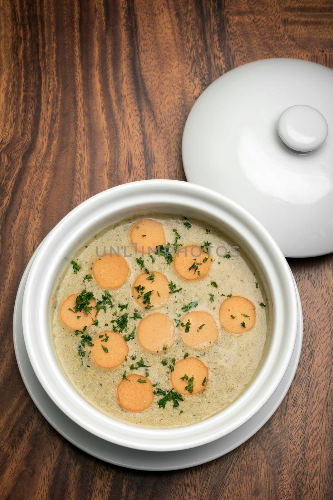 German traditional KARTOFFELSUPPE potato and sausage soup on wood table background